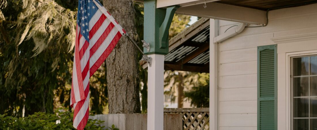 An American flag on the porch of a white house with green shutters, the family home the SCRA protects