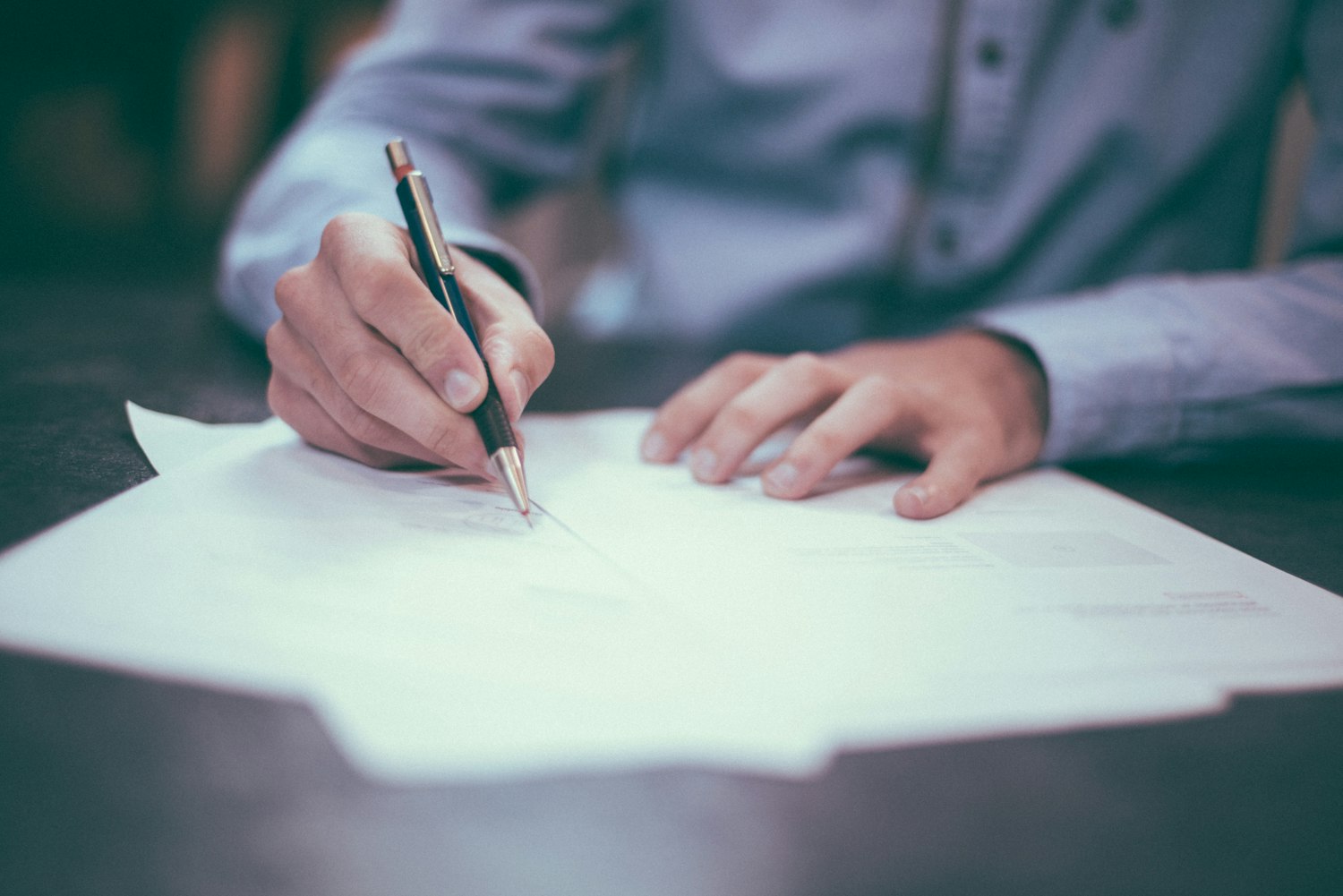 A person writing on paperwork, as when completing a discharge upgrade application